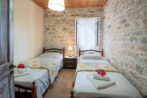 a bedroom with two beds and a brick wall at Ionian Stone Home with Terrace in Bogdanátika