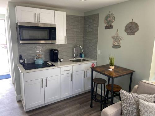 a kitchen with white cabinets and a sink and a table at 318 E Youngs Ave Unit 8 Salty Shore Retreat Idyllic Studio by the Sea in Wildwood