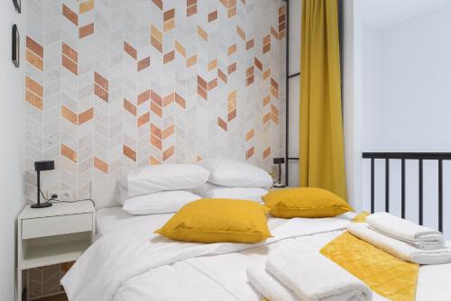 una camera da letto con un letto bianco con cuscini gialli di City Break P&O Apartments Olbrachta - Wola a Varsavia
