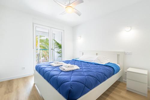 - une chambre avec un lit doté de draps bleus et une fenêtre dans l'établissement Copacabana Apartment 4-C Levante Beach, à Benidorm