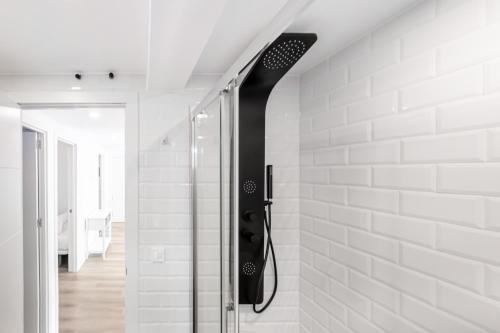 La salle de bains est pourvue d'une douche et de murs blancs. dans l'établissement Copacabana Apartment 4-C Levante Beach, à Benidorm