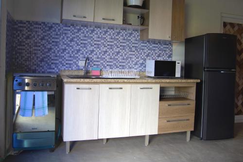 a kitchen with a black refrigerator and a counter top at El Arrecife Martin Pescador in Taxisco