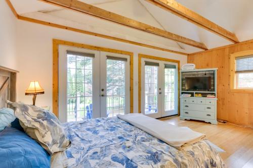 a bedroom with a bed and a tv and windows at East Otis Vacation Rental with Private Deck and BBQ! in East Otis