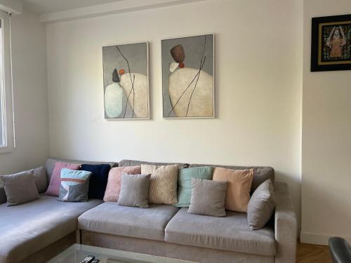 a living room with a couch with three paintings on the wall at Nice stay in city center with Parking in Boulogne-Billancourt