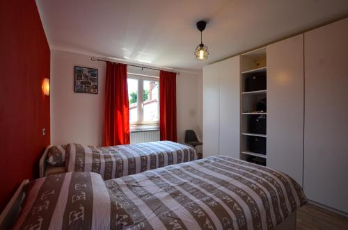 1 dormitorio con 2 camas y una ventana con cortinas rojas en Noemi & Ana Apartment, en Rovinj
