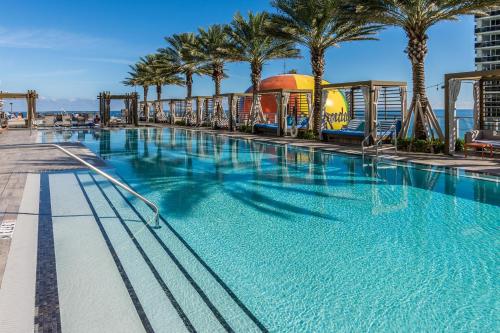 a large swimming pool with palm trees and a roller coaster at PRICE REDUCED DUE TO FLOOR COSMETIC DAMAGE - Picturesque Beachfront Condo - LOVELY 2BD and 2BA APT WITH DIRECT OCEAN VIEW in Hollywood