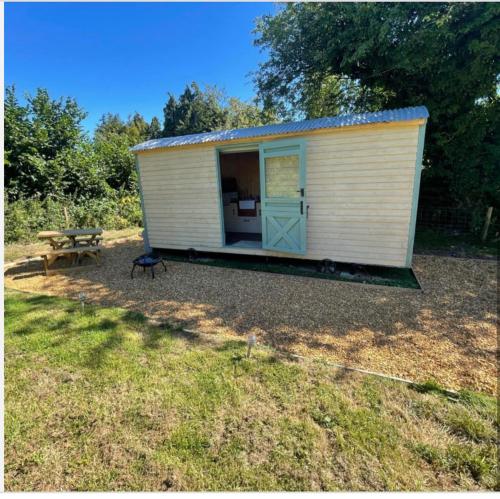 un pequeño cobertizo blanco con una mesa de picnic y un banco en Cosycoopmiskineggs, en Llantrisant