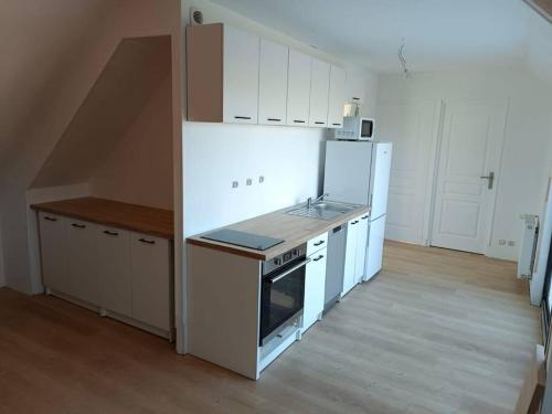 cocina con fogones y nevera blanca en Appartement lumineux avec terrasse !, en Plonéour-Lanvern