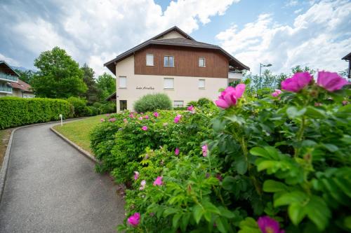 une maison avec des fleurs roses en face d'une allée dans l'établissement Lac et montagnes charmant appartement au calme pour 4 personnes, à Saint-Jorioz