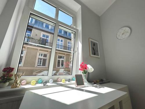 um quarto branco com uma janela e uma mesa com flores em MMRent Shadow Room em Gdansk
