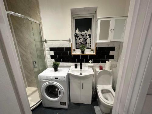 a bathroom with a toilet a sink and a washing machine at Guest&Rest 3 in London