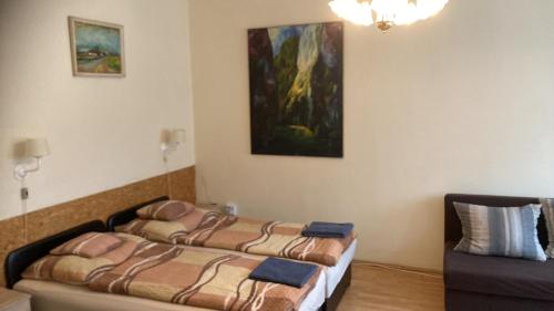 エゲルにあるBazis Guesthouseのベッド2台が備わる客室で、壁には絵画が飾られています。