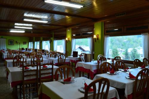 a dining room with white tables and chairs and windows at Hostal l'Escon in Llanars