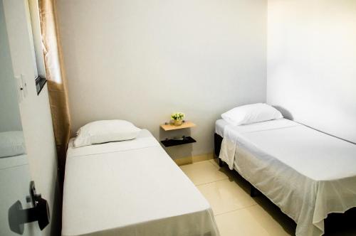 Cette chambre comprend deux lits et une petite table. dans l'établissement Apartamento novo e completo no Centro de Palmas c/ internet, à Palmas