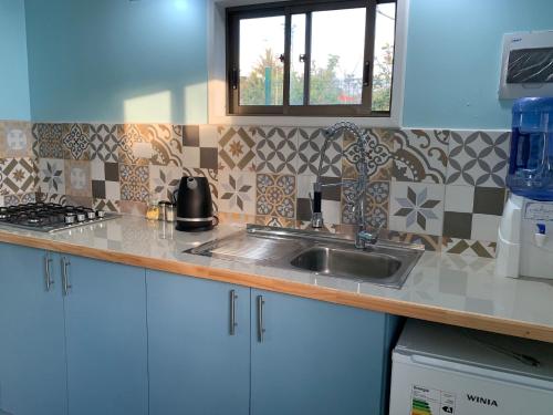 eine Küchentheke mit einem Waschbecken und einem Fenster in der Unterkunft Cabañas Raupa in Hanga Roa