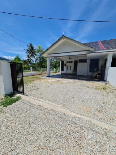 a house with a gravel driveway in front of it at OLIA MEDINA KERTEH 4 BILIK HOMESTaY in Kemaman