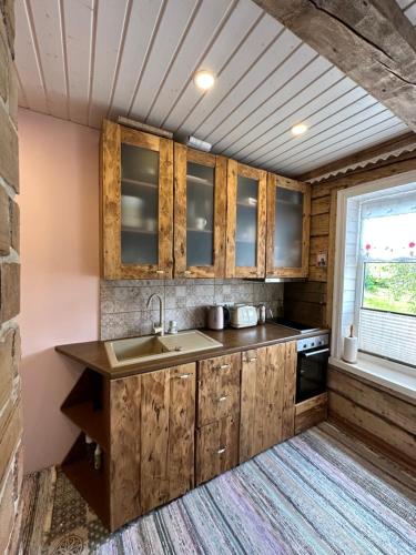 a kitchen with wooden cabinets and a sink and a window at Sadama Apartement Haapsalu in Haapsalu