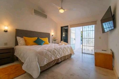 a bedroom with a large bed with yellow and blue pillows at Casa Jocelyne Alberca Privada in Puerto Vallarta