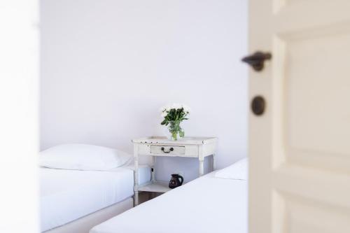 a white bedroom with a bed and a nightstand at The Beach House in Néa Péramos