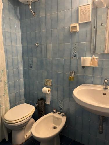 a blue tiled bathroom with a toilet and a sink at Hotel Nice in Viareggio