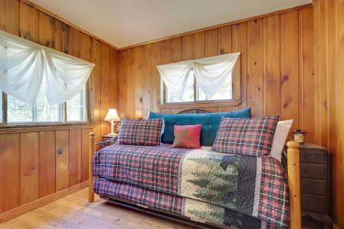 Cama en habitación con paredes y ventanas de madera en Charlevoix Cabin with Patio and Grill - Steps to Lake! en Charlevoix