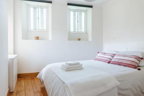 1 dormitorio blanco con 1 cama y 2 ventanas en Lisboa - São Lázaro Central Apartment, en Lisboa