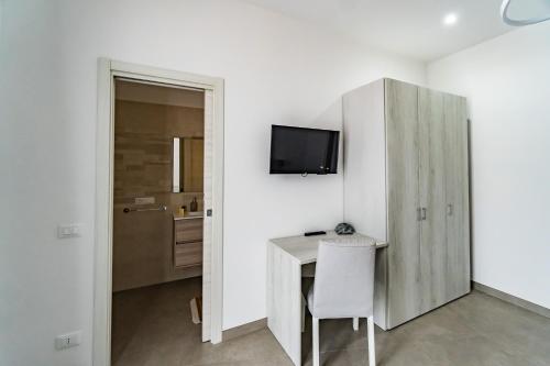 a white room with a desk and a tv on a wall at Appartamenti Petali Di Rosa in Custonaci