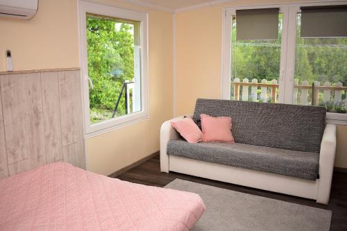 salon z kanapą i dwoma oknami w obiekcie Liliom Apartman w mieście Balatonvilágos