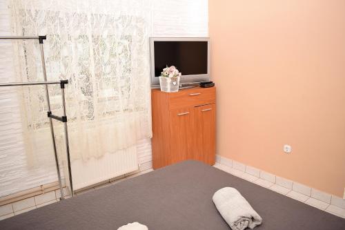 1 dormitorio con TV en un tocador y 1 cama en Liliom Apartman, en Balatonvilágos