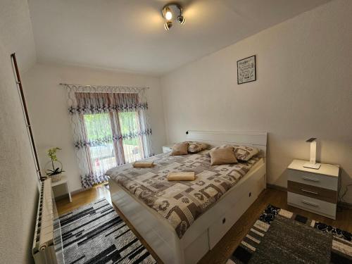 ein Schlafzimmer mit einem großen Bett und einem Fenster in der Unterkunft Apartment Topalović in Korenica