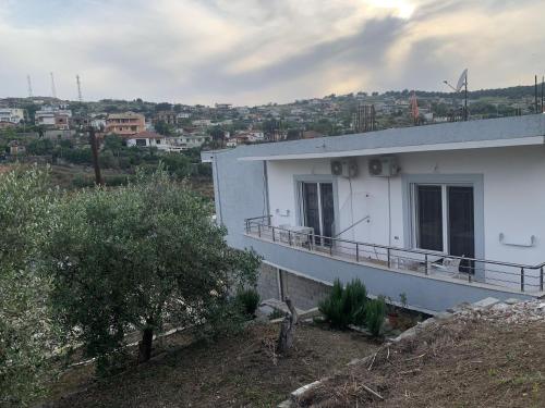 a white building with a balcony on a hill at Vila HALIM BANI in Sarandë