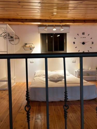 1 dormitorio con 1 cama con reloj en la pared en ״יעד״ יחידת דיור כפרית en ‘Akko
