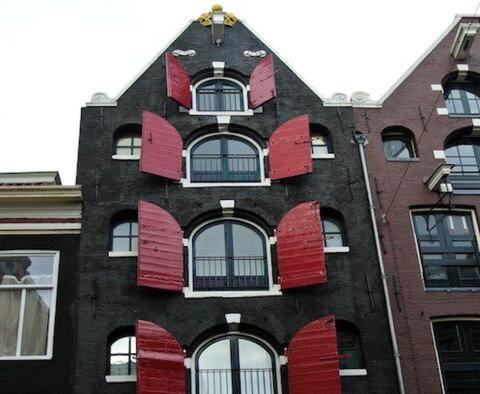 a building with red shutters on the side of it at Crown Guesthouse Amsterdam in Amsterdam