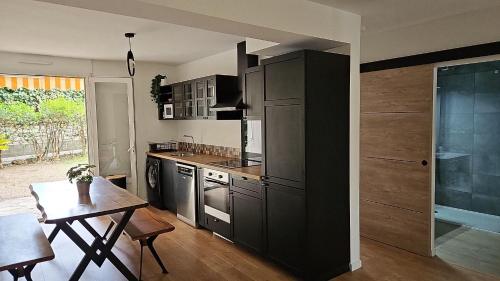 a kitchen with black cabinets and a table in it at T4 Proche centre et plages Jacuzzi et Parking gratuit in Montpellier