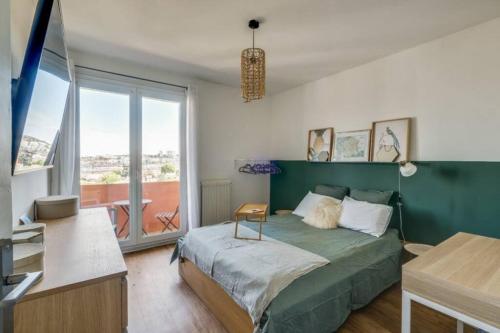 - une chambre avec un lit vert et un balcon dans l'établissement Le Minimes : vue de rêve au coeur de Toulouse, à Toulouse