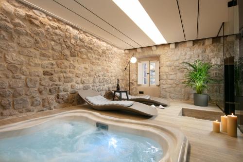 a hot tub in a room with a stone wall at Villa Lapisa in Dubrovnik