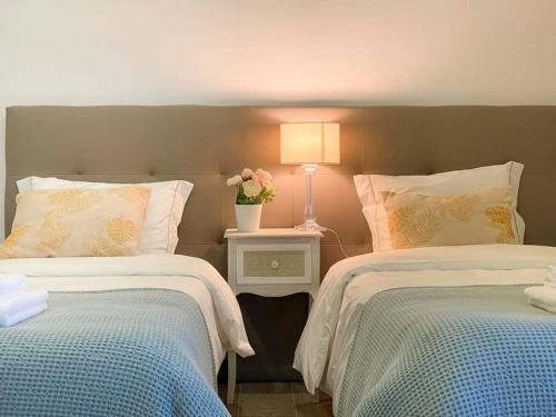 a bedroom with two beds and a table with a lamp at Capelas House Family in Capelas