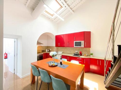 een keuken met rode kasten en een houten tafel en stoelen bij Capelas House Family in Capelas