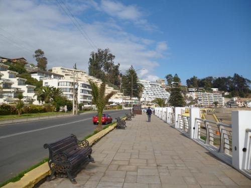 a person walking down a sidewalk next to a street at Departamento Frente al Mar in Concón