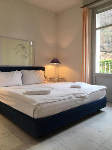 a large bed in a bedroom with a window at Ville Lago Lugano in Porto Ceresio