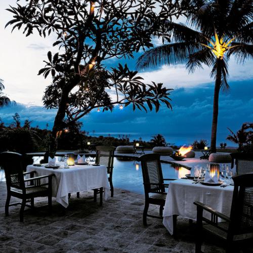 a restaurant with tables and chairs in front of a pool at The Damai in Lovina
