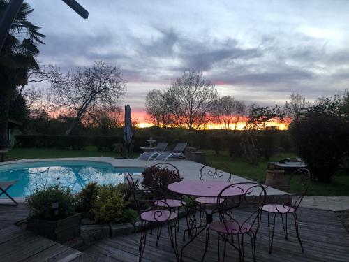 a patio with a table and chairs next to a pool at Maison de Paille in Ceton
