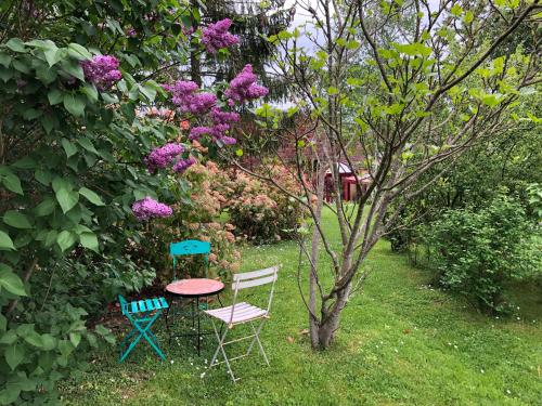 two chairs and a table in a garden with flowers at Maison de Paille in Ceton
