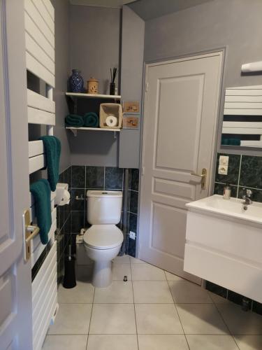 baño con aseo, lavabo y puerta en Maison de Paille, en Ceton