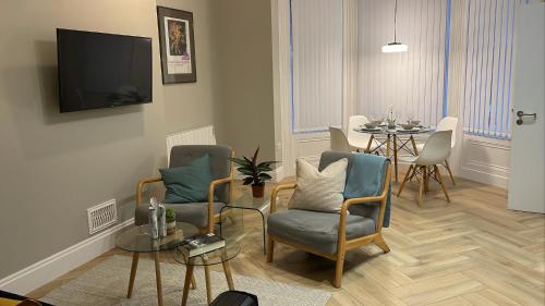 ein Wohnzimmer mit einem Tisch, Stühlen und einem TV in der Unterkunft CityGo Apartments Queens in Belfast