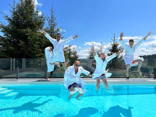 a group of men jumping into a swimming pool at be be Chalet - premium jacuzi & private pool in Bukovel