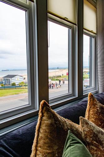 a living room with windows looking out at the beach at The Canoeists Hideaway in Seaton Carew