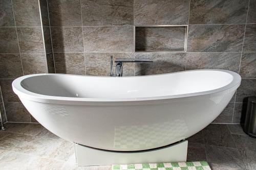 a white bath tub in a bathroom with a tile wall at The Canoeists Hideaway in Seaton Carew