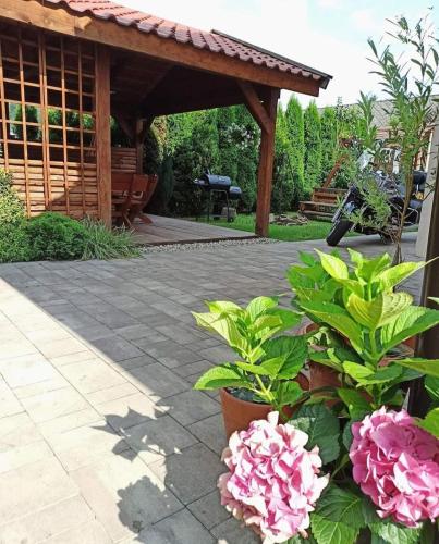 a patio with pink flowers and a pavilion at Rodzinny zakątek - Noclegi w Bieszczadach - jacuzzi in Myczkowce