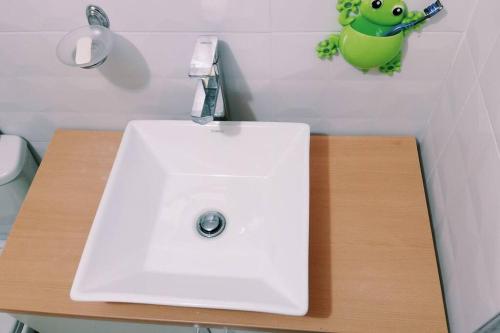 ein weißes Waschbecken im Bad mit einem Frosch an der Wand in der Unterkunft Departamento: Mirador de Puno. in Puno